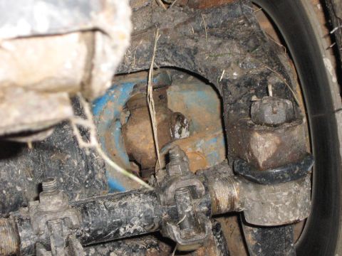 1986 Ford Bronco - This image shows a close-up view of the dirty suspension components of a vehicle, with a tire visible on the right.
