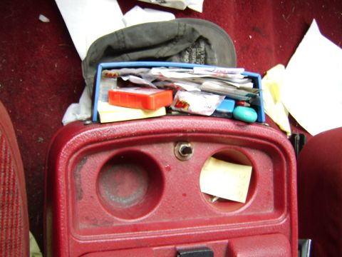 1989 Ford Bronco - Cluttered center console with various items inside and on top.