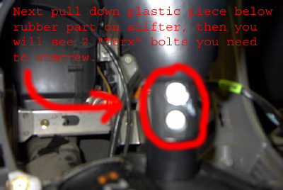 1999 Ford Taurus - Close-up of car interior showing a shifter mechanism with red arrows and circles pointing to bolts.