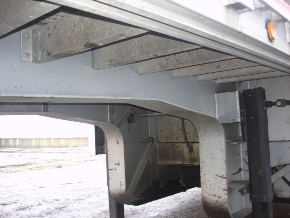 Undercarriage of a trailer with visible structural beams and a jack