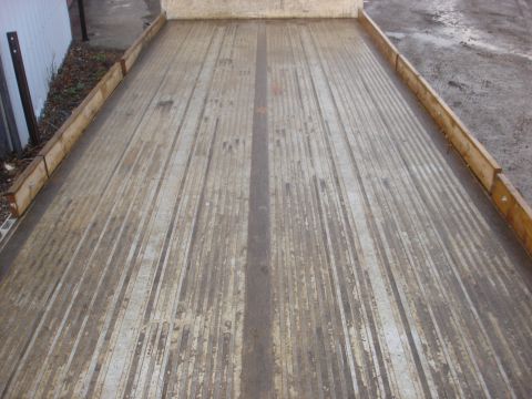 2006 Ford F-350 - The worn, ribbed metal floor of a flatbed truck's cargo area is visible, with wooden side rails.