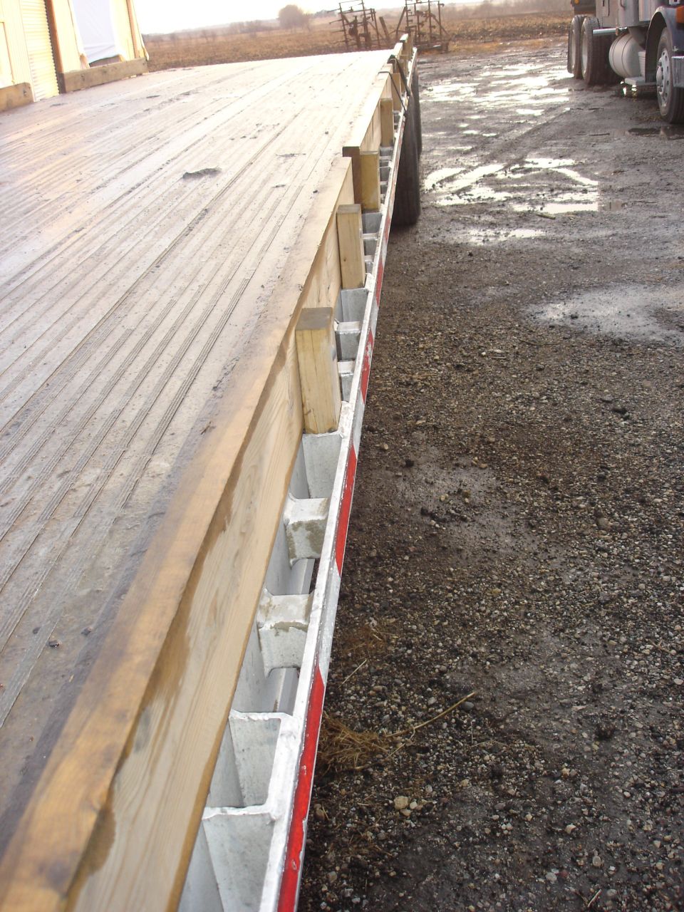 Flatbed trailer side view with a truck in the background