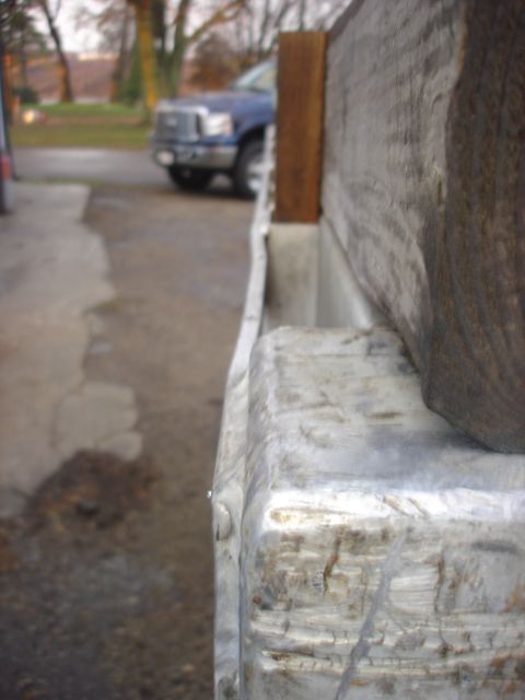 2006 Ford F-350 - A blue pickup truck is parked in front of a building, partially obscured by a wooden post.