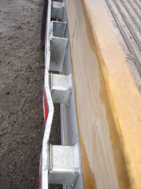 2006 Ford F-350 - Close-up view of a trailer's side rail construction, showing metal and wood components.