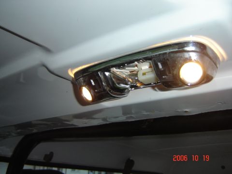 1993 Ford Bronco - The interior dome light assembly shows chrome accents and two lit bulbs, with a date stamp of 2006.