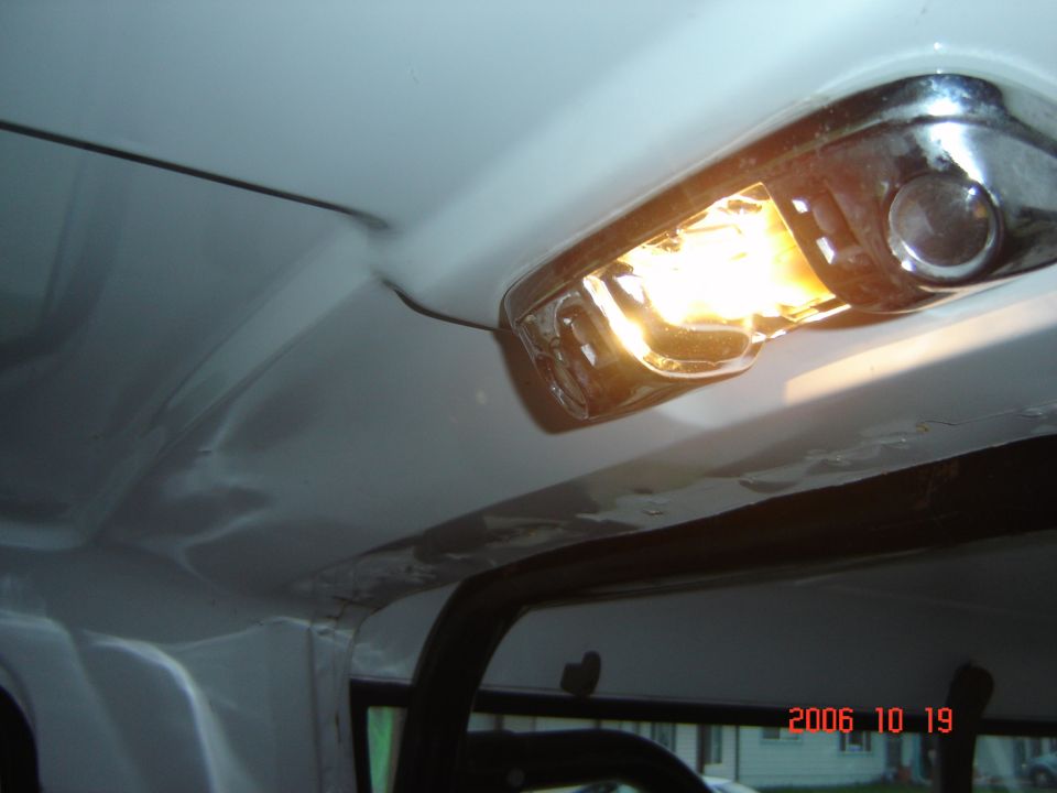 Lit chrome dome light on bare white metal roof with headliner removed