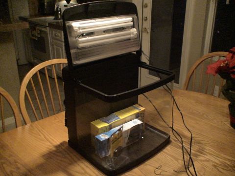 1993 Ford C-350 (Centurion Conversions) - An aquarium setup with lights is displayed on a wooden table, with boxes inside the tank.
