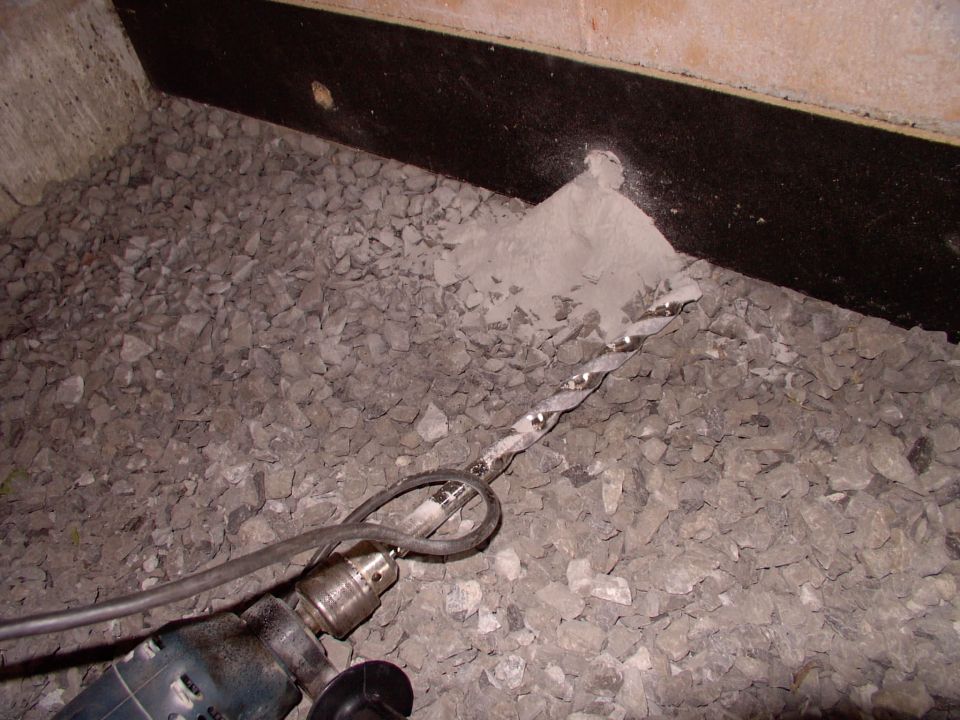 Two 3/4" holes drilled into the 10" poured basement wall nearly wasted the old hammer drill, but they're necessary to pass the PEX in and out. Note the black joe glued onto the walls for thermal separation to allow expansion.