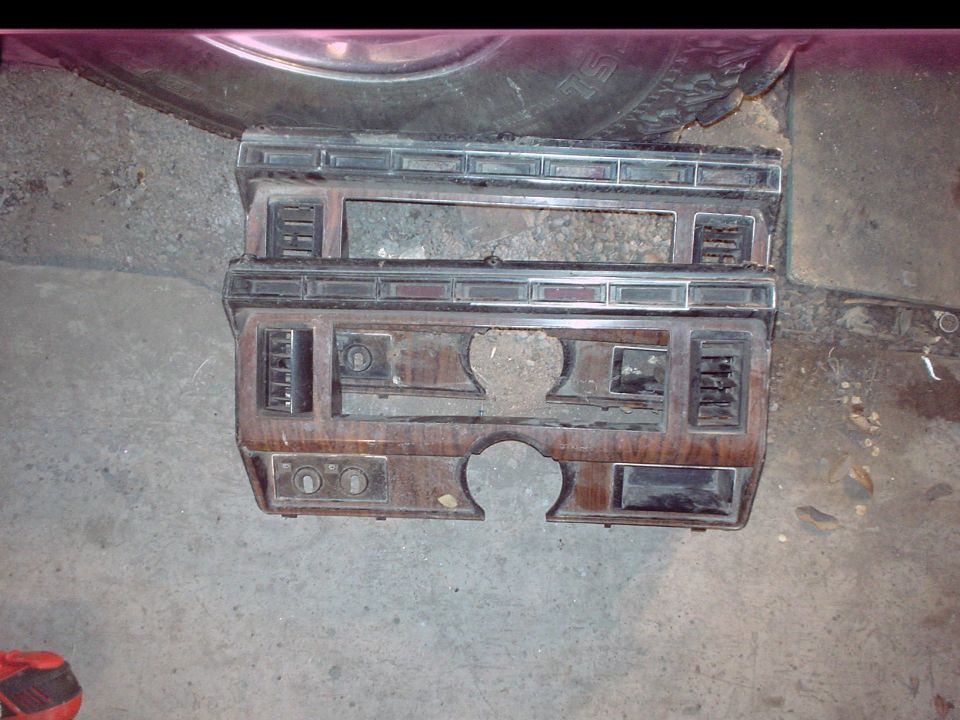 Two woodgrain dash bezels removed from a truck lying on a concrete garage floor