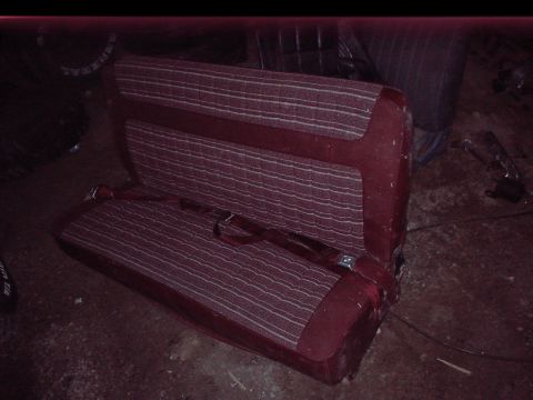 1984 Ford Bronco - Maroon car seat with striped fabric and a seatbelt is shown.
