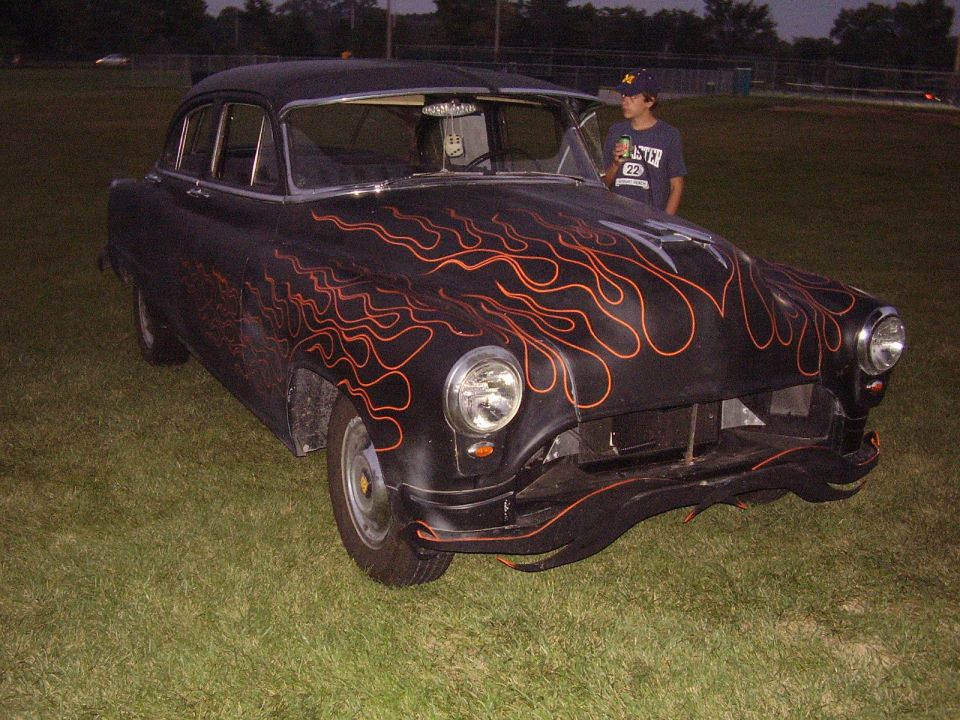Black sedan with orange flame decals, front quarter view, parked on grass