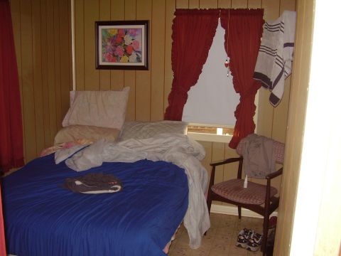 1996 Ford F-150 - Interior view of a bedroom with wood-paneled walls and a window covered by red curtains.
