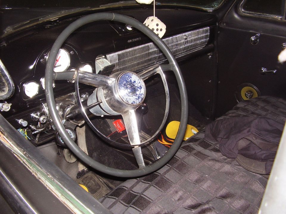 Interior view of a vintage car with a large steering wheel and chrome accents