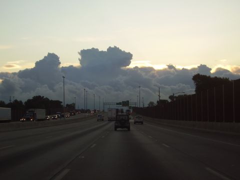1996 Ford F-150 - A dark Jeep Wrangler travels down a highway under a dramatic sky filled with large clouds.