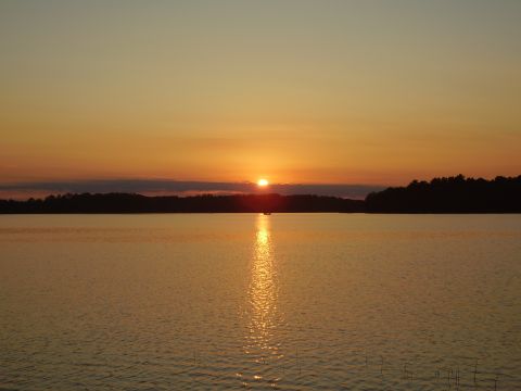1996 Ford F-150 - Sunset over a lake with a distant boat and treeline.