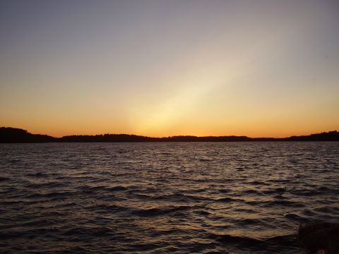 1996 Ford F-150 - A sunset paints the sky with warm colors over a calm lake, with a dark tree line silhouetted against the horizon.
