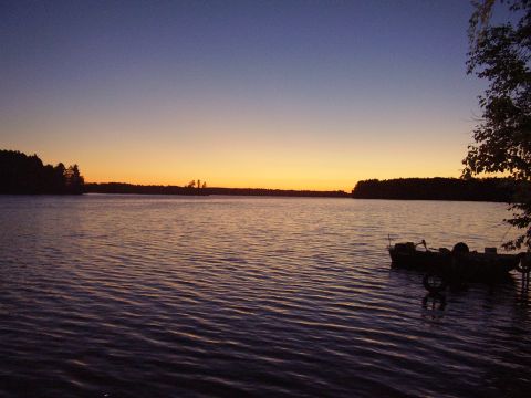 1996 Ford F-150 - A boat is docked on a lake as the sun sets, casting a warm glow across the sky.