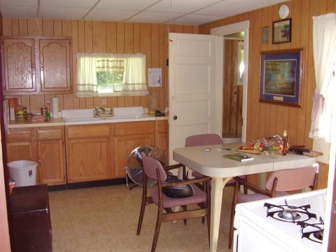 1996 Ford F-150 - Interior view of a kitchen wood paneled walls, a dining table with chairs, and a stove.