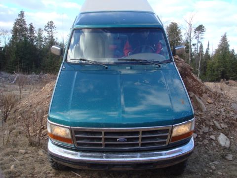 1996 Ford Bronco - Front view of a teal van with a chrome grille and Ford emblem, parked outdoors.