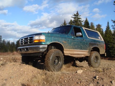 1996 Ford Bronco - A green 1996 Ford Bronco is shown off-road with a lifted suspension and large tires.