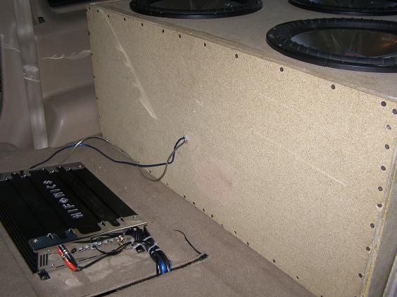 Bare MDF subwoofer box with two subs and a Hifonics amp in an SUV cargo area