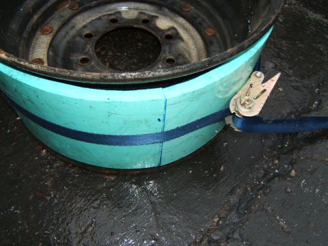1980 Jeep CJ5 - A close-up view of a wheel rim with teal padding and a blue strap, likely for transport or modification.