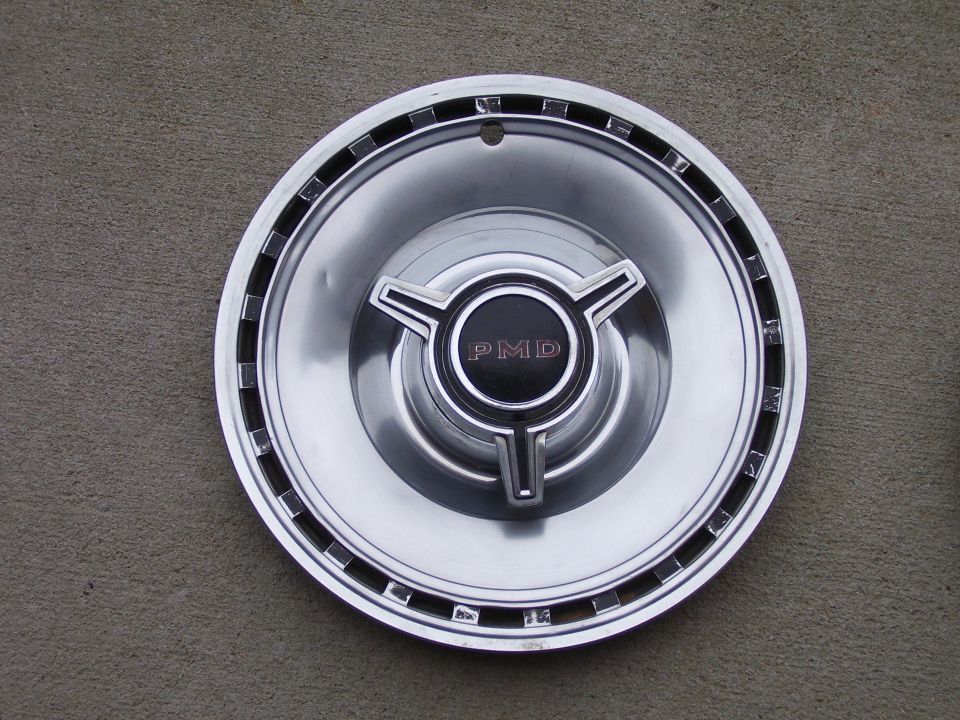 Chrome Pontiac PMD spinner hubcap with three-bar center cap on concrete