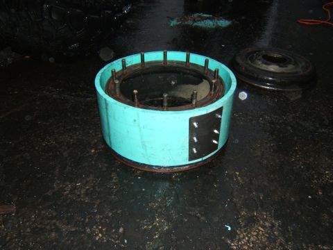 1980 Jeep CJ5 - A turquoise cylindrical part with protruding studs sits on a wet surface next to a tire.