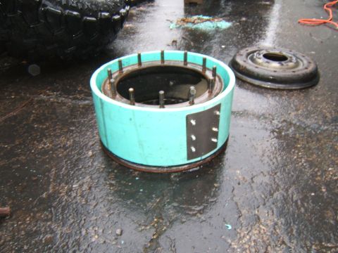1980 Jeep CJ5 - Automotive part with studs and a separate metal disc on wet ground, with a tire in the background.