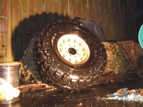 1980 Jeep CJ5 - Close-up of a large off-road tire and wheel assembly, partially obscured by netting.
