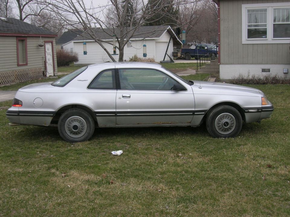 Silver 1987 Ford Thunderbird coupe parked on grass, side view
