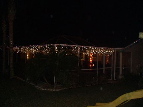 1993 Ford C-350 (Centurion Conversions) - A house is decorated with numerous strings of Christmas lights along the roofline and porch.