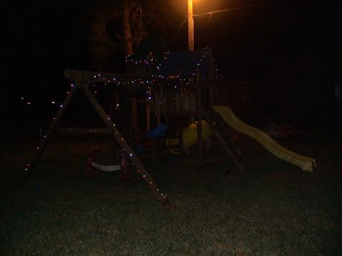1993 Ford C-350 (Centurion Conversions) - Wooden swing set illuminated by Christmas lights in the dark.
