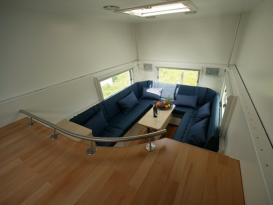 Interior of camper van with U-shaped blue seating and wooden floor