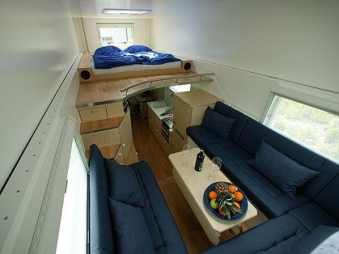1993 Ford Bronco - This RV interior features a sleeping loft, a galley kitchen, and a spacious lounge area with blue upholstery.