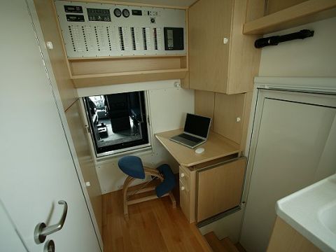 1993 Ford Bronco - The interior of a camper van features a workstation with a laptop and a comprehensive control panel above.