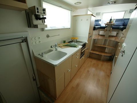 1993 Ford Bronco - RV interior shows a compact kitchen area and a raised seating section with blue upholstered benches.