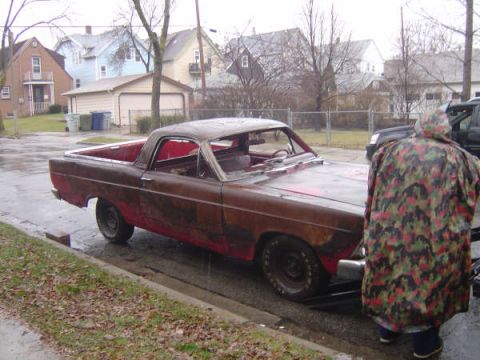 1973 Ford Ranchero - A weathered 1967 Ford Ranchero sits on the side of a street on a rainy day, with another vehicle partially visible behind it.