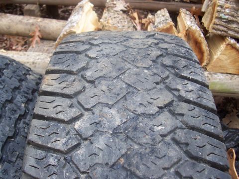 1994 Jeep YJ - A close-up view of a tire's tread pattern, with a second tire and firewood visible in the background.