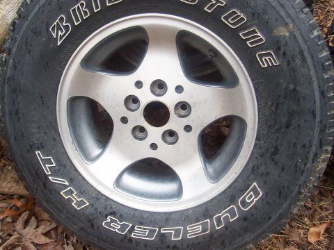 1994 Jeep YJ - A close-up of a Bridgestone Dueler H/T tire mounted on a five-spoke alloy wheel.