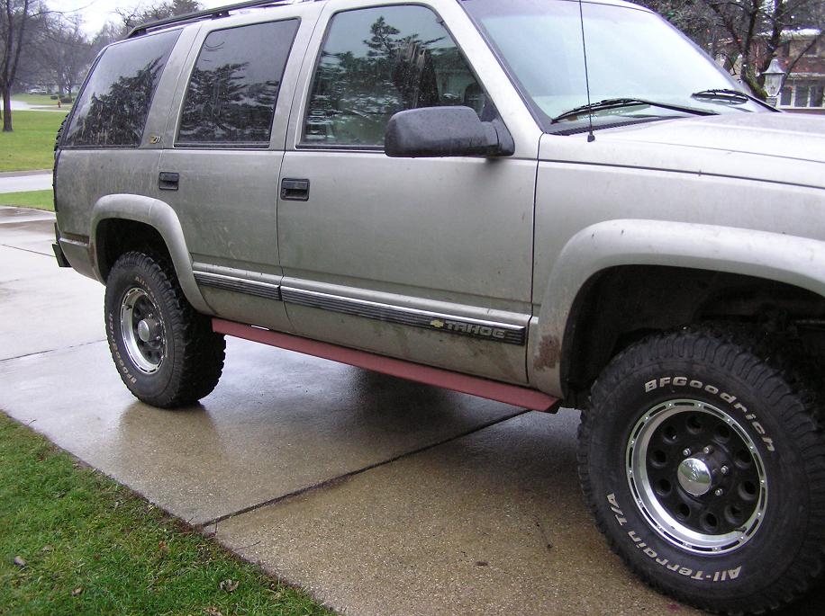 Silver 2000 Chevrolet Tahoe SUV with aftermarket red running boards, seen from the side