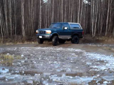1996 Ford Bronco - This 1996 Ford Bronco is parked on a dirt road with a forest behind it.