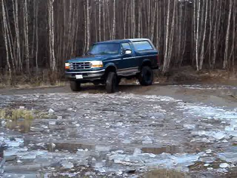 1996 Ford Bronco - This 1996 Ford Bronco is seen from a 3q front angle on a dirt road, with a backdrop of trees.