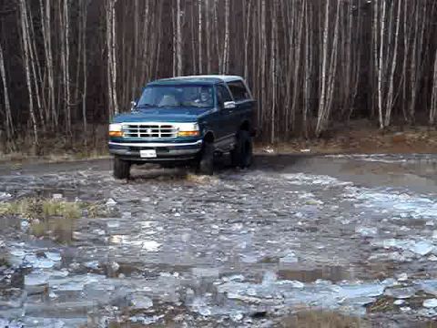 1996 Ford Bronco - 1996 Ford Bronco navigates an icy dirt road through a forest.
