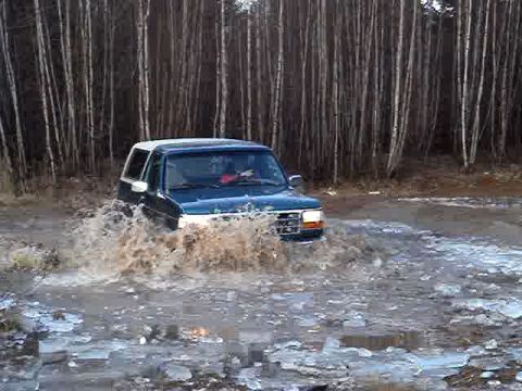1996 Ford Bronco - 1996 Ford Bronco navigating a water obstacle in a wooded area.