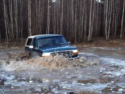 1996 Ford Bronco - A Ford Bronco navigates a flooded, icy terrain surrounded by a dense forest.