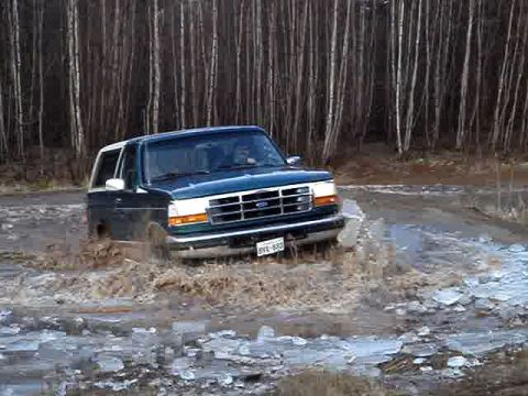 1996 Ford Bronco - 1996 Ford Bronco navigating a challenging off-road path with mud and ice.