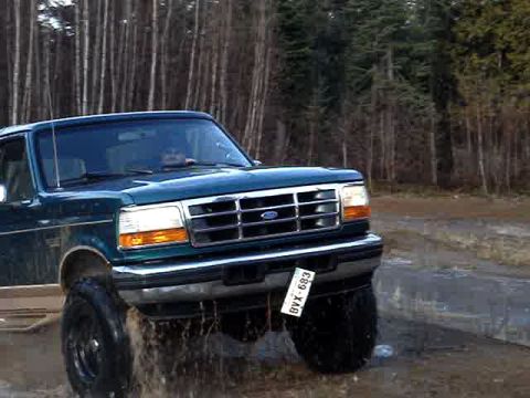 1996 Ford Bronco - This 1996 Ford Bronco is captured in a 3/4 front view as it drives through water, kicking up spray.