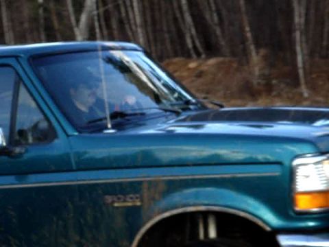 1996 Ford Bronco - A teal 1996 Ford Bronco is seen from the side, with a driver behind the wheel.