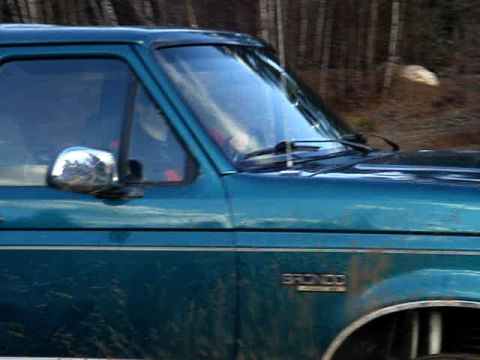 1996 Ford Bronco - Side view of a teal 1996 Ford Bronco, captured while driving through a wooded area.